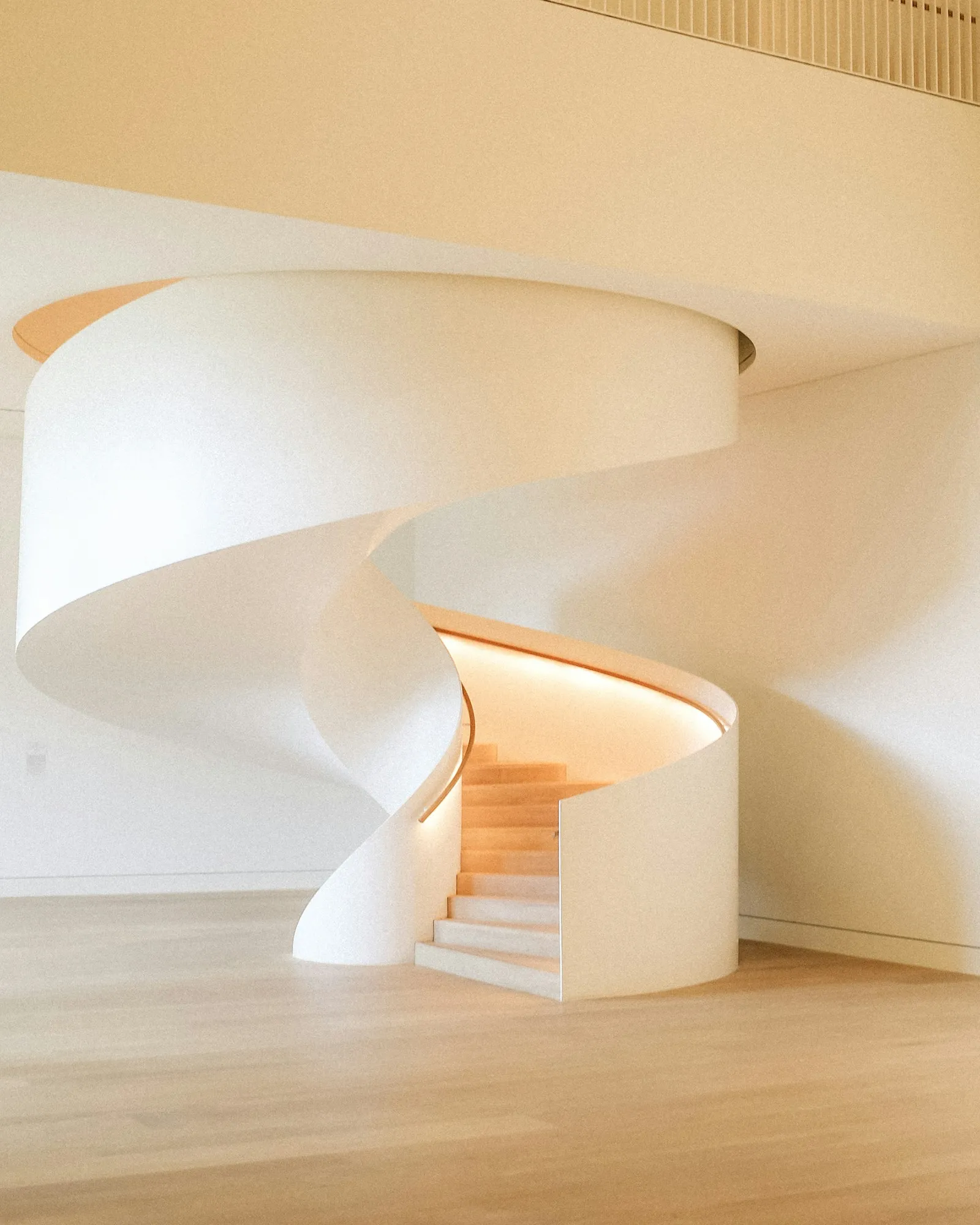 Sculptural curved staircase in warm stone tones