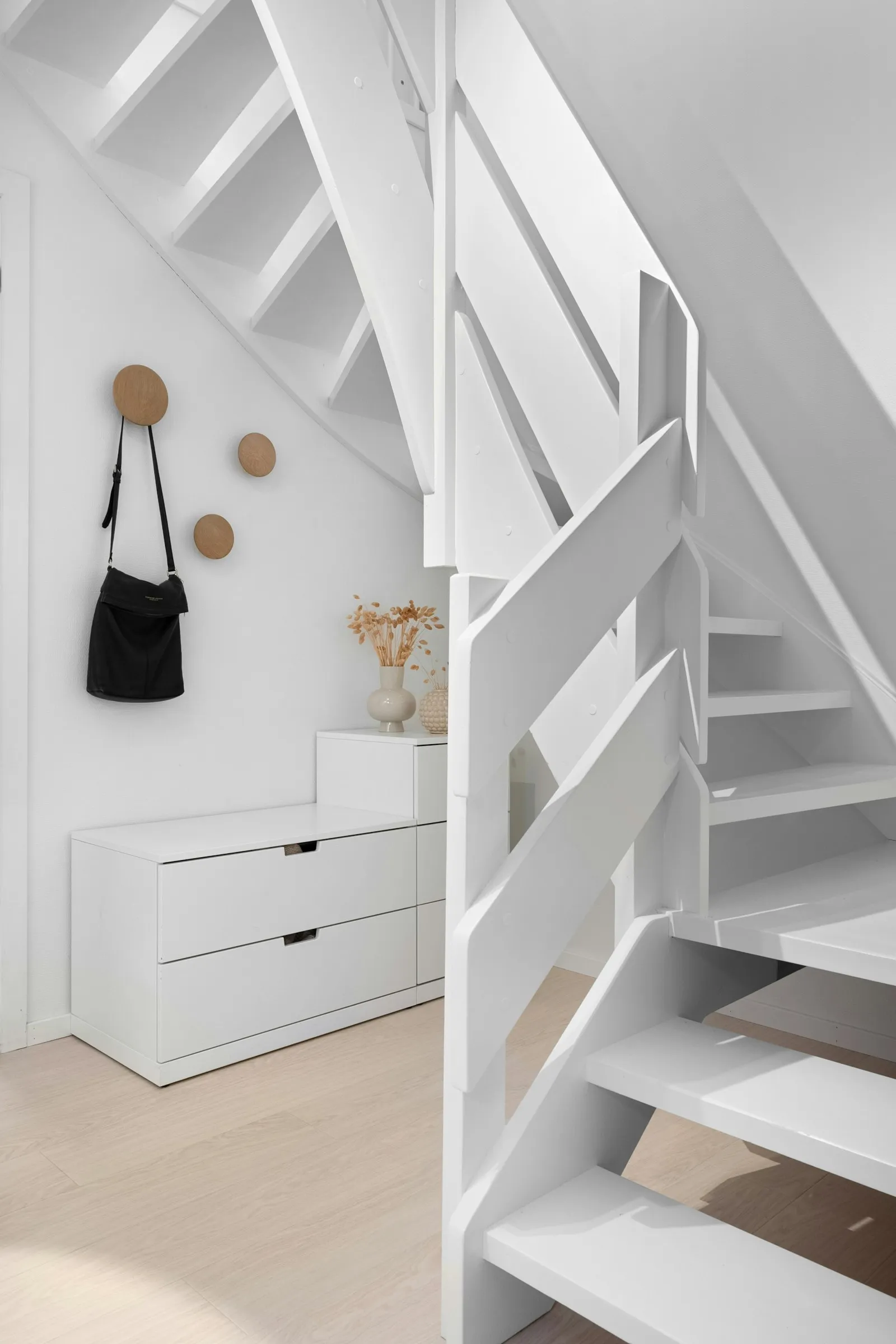 Bright residential interior with a white timber staircase and oak floor