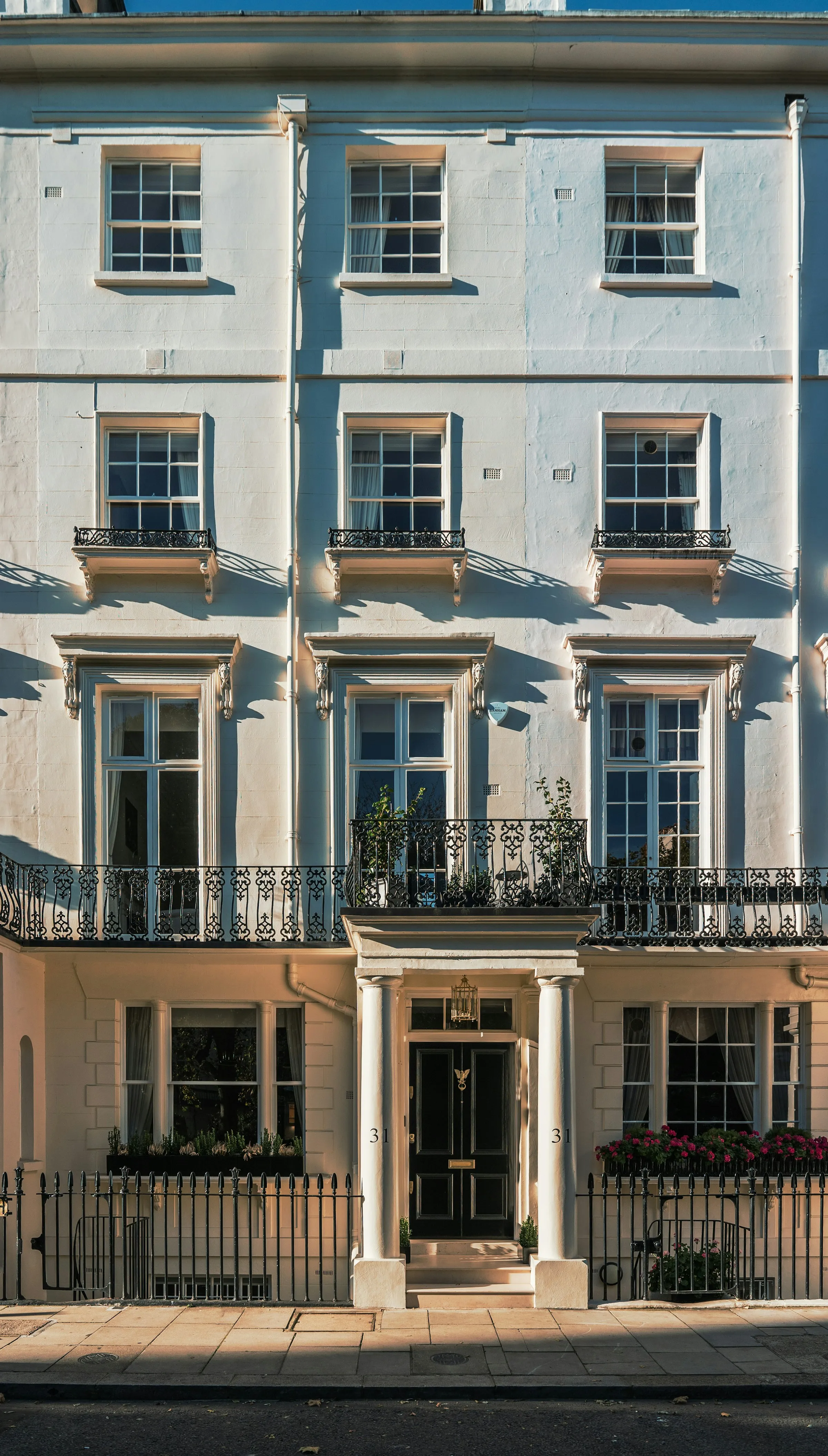 Sunlight across the stone façade and iron balconies of a London townhouse